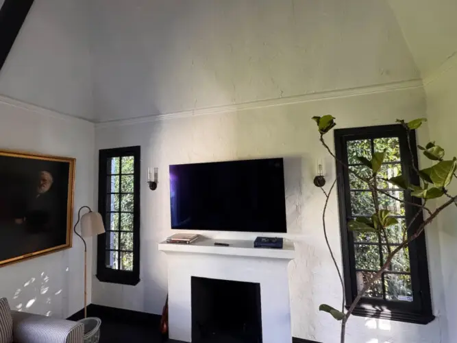 Fireplace and TV in a room with a large window at Beverly Grove Tudor Family Home - by Open Air Homes.