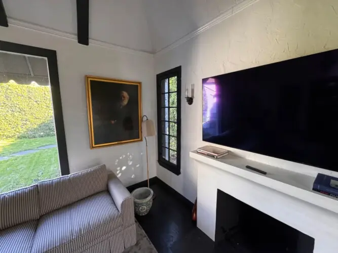 Living room with striped sofa, fireplace, and wall-mounted TV at Beverly Grove Tudor Family Home - by Open Air Homes.