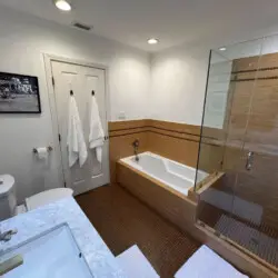 Bathroom with bathtub and glass-enclosed shower at Beverly Grove Tudor Family Home - by Open Air Homes.