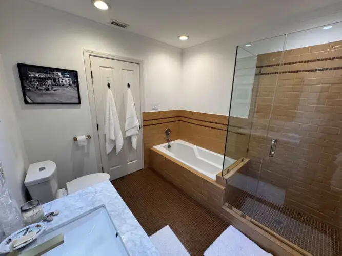 Bathroom with bathtub and glass-enclosed shower at Beverly Grove Tudor Family Home - by Open Air Homes.