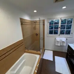 Bathroom with bathtub and glass-enclosed shower at Beverly Grove Tudor Family Home - by Open Air Homes.