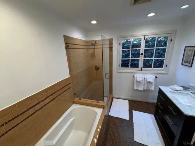 Bathroom with bathtub and glass-enclosed shower at Beverly Grove Tudor Family Home - by Open Air Homes.