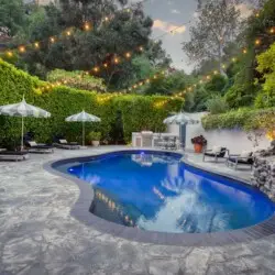 Exterior view of Laurel Canyon Classic Hollywood Residence W/ Pool with stone patio, lounge chairs, umbrellas, and swimming pool by Open Air Homes.