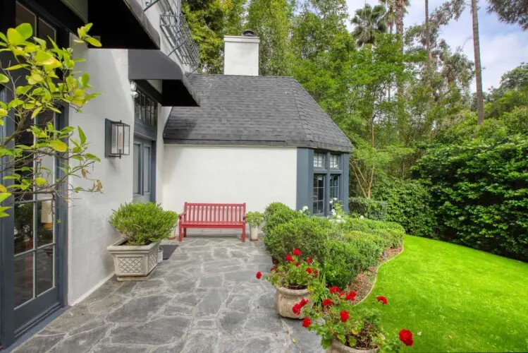 Exterior view of Laurel Canyon Classic Hollywood Residence W/ Pool with stone patio, bench, potted plants, and lawn by Open Air Homes.