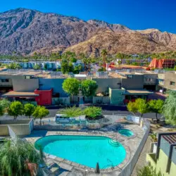 Outdoor view of the pool area with surrounding buildings and mountainous backdrop at La Mirage - by Open Air Homes