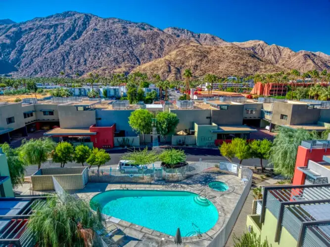 Outdoor view of the pool area with surrounding buildings and mountainous backdrop at La Mirage - by Open Air Homes