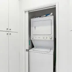 Laundry area with stacked washer and dryer in a closet at La Mirage gated community in Palm Springs, providing convenience for guests – by Open Air Homes.