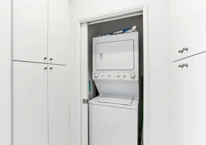 Laundry area with stacked washer and dryer in a closet at La Mirage gated community in Palm Springs, providing convenience for guests – by Open Air Homes.