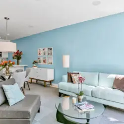 Living area with blue accent wall, sofa, chairs, and coffee table at La Mirage gated community in Palm Springs, featuring modern design – by Open Air Homes.