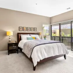 Bedroom with bed, side table, lamp, and sliding glass doors leading to a balcony at La Mirage - by Open Air Homes