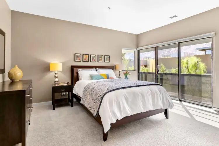 Bedroom with bed, side table, lamp, and sliding glass doors leading to a balcony at La Mirage - by Open Air Homes