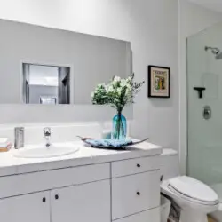 Bathroom with sink, mirror, and glass-enclosed shower at La Mirage gated community in Palm Springs, showcasing modern design – by Open Air Homes.