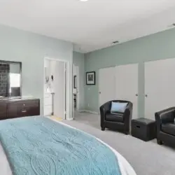 Bedroom with bed, two armchairs, and dresser at La Mirage gated community in Palm Springs, offering a comfortable and inviting space – by Open Air Homes.