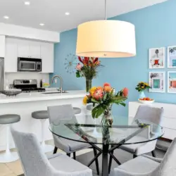 Modern kitchen and dining area with blue accent wall, white island, and dining table at La Mirage gated community in Palm Springs – by Open Air Homes.