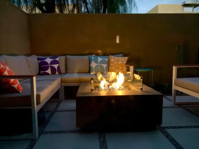 Outdoor seating area with fire pit and cushioned seating at La Mirage - by Open Air Homes