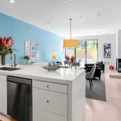 Kitchen with blue accent wall, white island, and dining area at La Mirage gated community in Palm Springs, featuring modern design – by Open Air Homes.