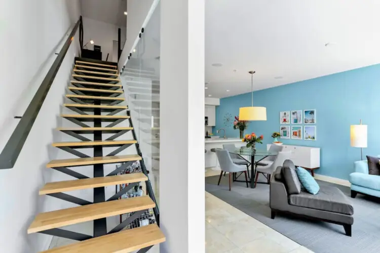 Modern staircase leading to upper level with view of living area at La Mirage gated community in Palm Springs, showcasing contemporary design – by Open Air Homes.