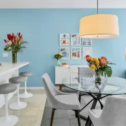 Dining area with blue accent wall, white island, and table with chairs at La Mirage gated community in Palm Springs, featuring a modern design – by Open Air Homes.