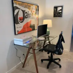 Glass desk workspace with office chair, computer monitor, and lamp at La Mirage gated community in Palm Springs, providing a comfortable and modern work area – by Open Air Homes.