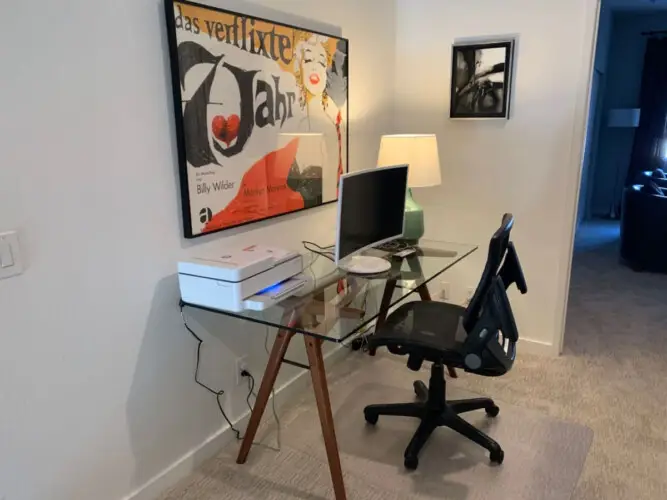 Glass desk workspace with office chair, computer monitor, and lamp at La Mirage gated community in Palm Springs, providing a comfortable and modern work area – by Open Air Homes.