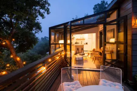 Outdoor patio with string lights, comfortable seating, and view into the interior of Canyon Crest Cottage and Garden – by Open Air Homes.