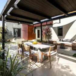 Outdoor dining area with table and chairs under a pergola at Sun-Drenched Spanish Manor in Mar Vista - by Open Air Homes.