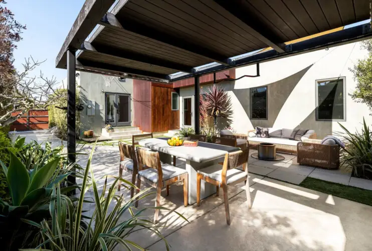 Outdoor dining area with table and chairs under a pergola at Sun-Drenched Spanish Manor in Mar Vista - by Open Air Homes.