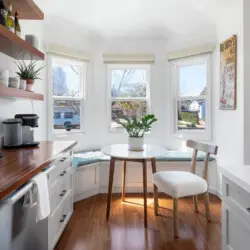 Cozy kitchen nook with round table, chairs, and bench seat by the window at Sun-Drenched Spanish Manor in Mar Vista - by Open Air Homes.