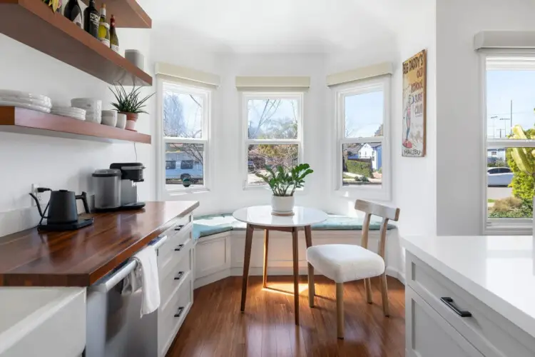 Cozy kitchen nook with round table, chairs, and bench seat by the window at Sun-Drenched Spanish Manor in Mar Vista - by Open Air Homes.