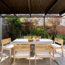 Outdoor dining area with table and chairs under a pergola at Sun-Drenched Spanish Manor in Mar Vista - by Open Air Homes.