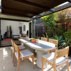 Outdoor dining area with table and chairs under a pergola at Sun-Drenched Spanish Manor in Mar Vista - by Open Air Homes.