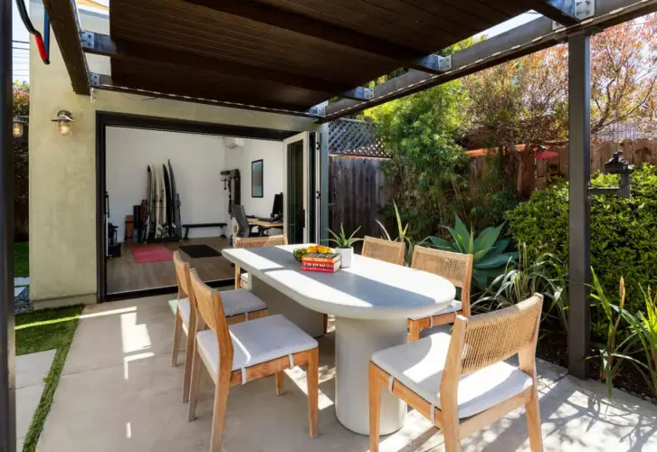 Outdoor dining area with table and chairs under a pergola at Sun-Drenched Spanish Manor in Mar Vista - by Open Air Homes.