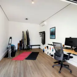 Multipurpose room with a desk, chairs, and surfboards at Sun-Drenched Spanish Manor in Mar Vista - by Open Air Homes.