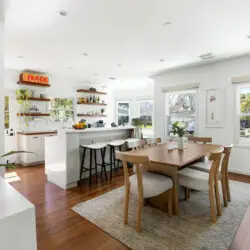 Dining area with wooden table and chairs, view of kitchen at Sun-Drenched Spanish Manor in Mar Vista - by Open Air Homes.