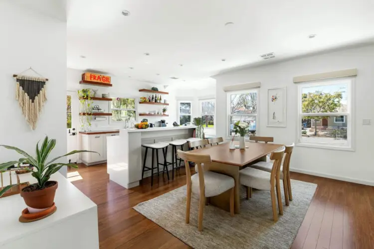 Dining area with wooden table and chairs, view of kitchen at Sun-Drenched Spanish Manor in Mar Vista - by Open Air Homes.