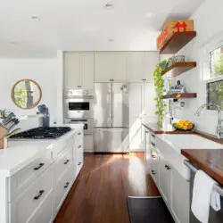 Bright kitchen with white cabinets, wooden countertops, and open shelving at Sun-Drenched Spanish Manor in Mar Vista - by Open Air Homes.