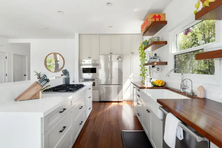 Bright kitchen with white cabinets, wooden countertops, and open shelving at Sun-Drenched Spanish Manor in Mar Vista - by Open Air Homes.