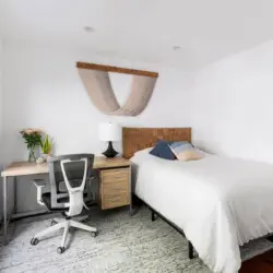 Bedroom with bed, bedside table, window, and desk with chair at Sun-Drenched Spanish Manor in Mar Vista - by Open Air Homes.