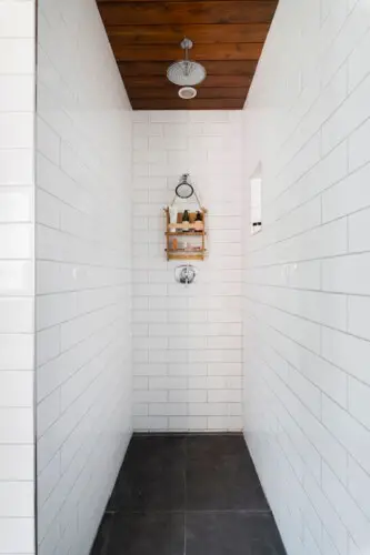 Shower area with white tiles and wooden ceiling at Sun-Drenched Spanish Manor in Mar Vista - by Open Air Homes.