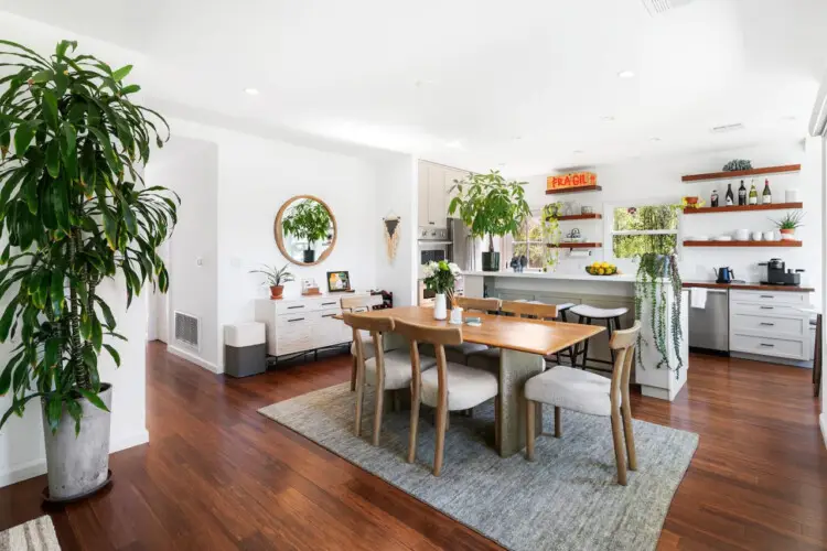 Dining area with wooden table and chairs, view of kitchen at Sun-Drenched Spanish Manor in Mar Vista - by Open Air Homes.