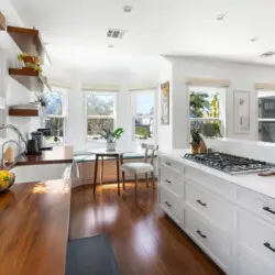 Bright kitchen with wooden countertops, white cabinets, and dining area at Sun-Drenched Spanish Manor in Mar Vista - by Open Air Homes.