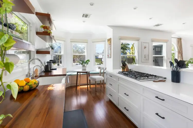 Bright kitchen with wooden countertops, white cabinets, and dining area at Sun-Drenched Spanish Manor in Mar Vista - by Open Air Homes.