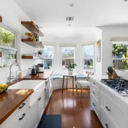 Bright kitchen with wooden countertops, white cabinets, and dining area at Sun-Drenched Spanish Manor in Mar Vista - by Open Air Homes.