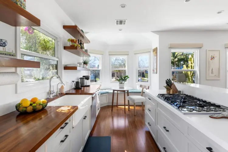 Bright kitchen with wooden countertops, white cabinets, and dining area at Sun-Drenched Spanish Manor in Mar Vista - by Open Air Homes.