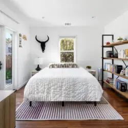 Bright bedroom with bed, bedside table, large windows, and stylish decor at Sun-Drenched Spanish Manor in Mar Vista - by Open Air Homes.