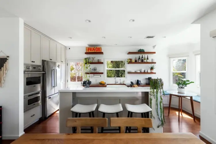 Bright kitchen with white cabinets, wooden countertops, and open shelving at Sun-Drenched Spanish Manor in Mar Vista - by Open Air Homes.