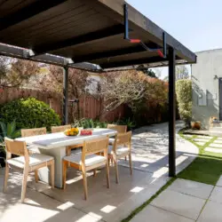 Outdoor dining area with table and chairs under a pergola at Sun-Drenched Spanish Manor in Mar Vista - by Open Air Homes.