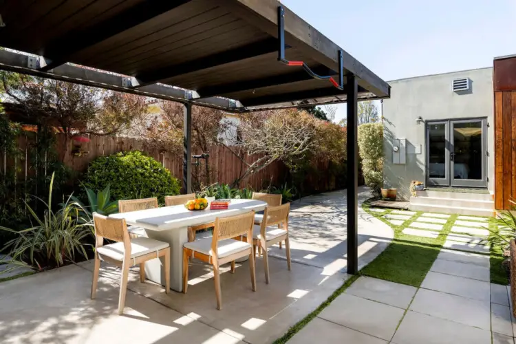 Outdoor dining area with table and chairs under a pergola at Sun-Drenched Spanish Manor in Mar Vista - by Open Air Homes.