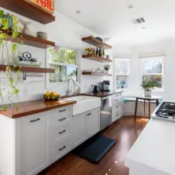 Bright kitchen with white cabinets, wooden countertops, and open shelving at Sun-Drenched Spanish Manor in Mar Vista - by Open Air Homes.