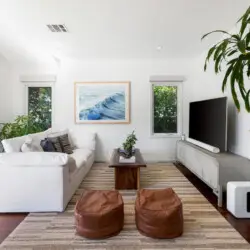 Living room with white sofa, rectangular coffee table, and large window at Sun-Drenched Spanish Manor in Mar Vista - by Open Air Homes.